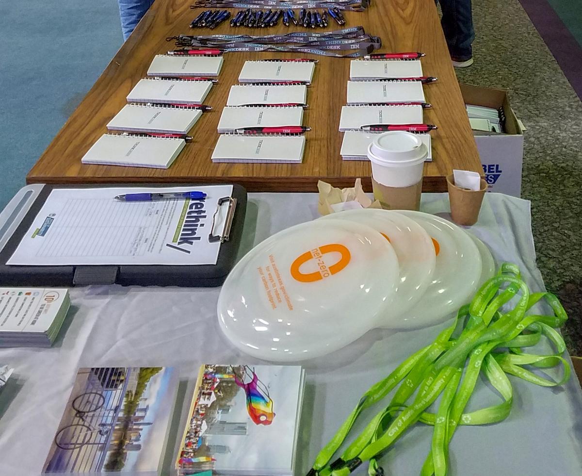 Close-up of outreach materials on a table. Glow in the dark frisbees are on the table as well as lime green lanyards.
