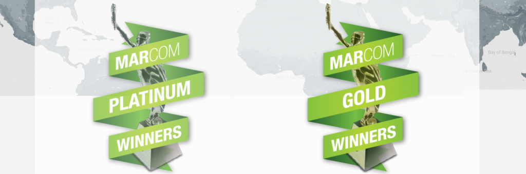 Graphic with a light grey world map in the background and two green ribbons in the foreground that read Marcom Platinum Winners and Marcom Gold Winners